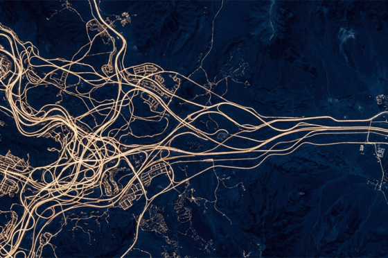 Luftbild eines komplexen Autobahn- und Straßennetzes mit zahlreichen Kreuzungen und Verbindungen, dargestellt auf dunkelblauem Hintergrund.